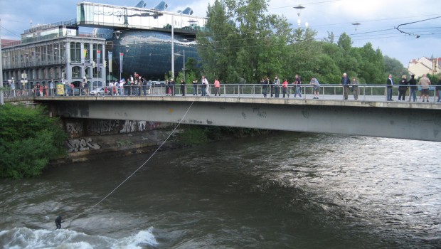 River surfing in Graz on the river Mur at the Hauptbrücke (main bridge).